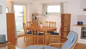 A cozy room with a wooden dining table, chairs, a sofa, a TV, and a kitchen area. - Hausboot in Kroeslin am Bodden (Kröslin)