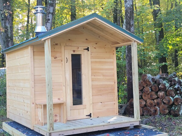 A wooden cabin with a pitched roof, a door, and a chimney. - The Chicken Coop at the Farm at Hyde Park (Staatsburg)
