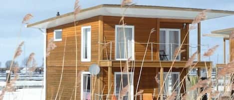 Una cabaña de madera con balcón, varias ventanas y una antena parabólica.