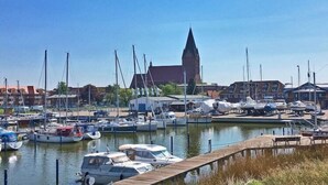 A marina with boats docked, a church with a tall steeple, and buildings in the background. - Hausboot in Barth am Barther Bodden (Barth)