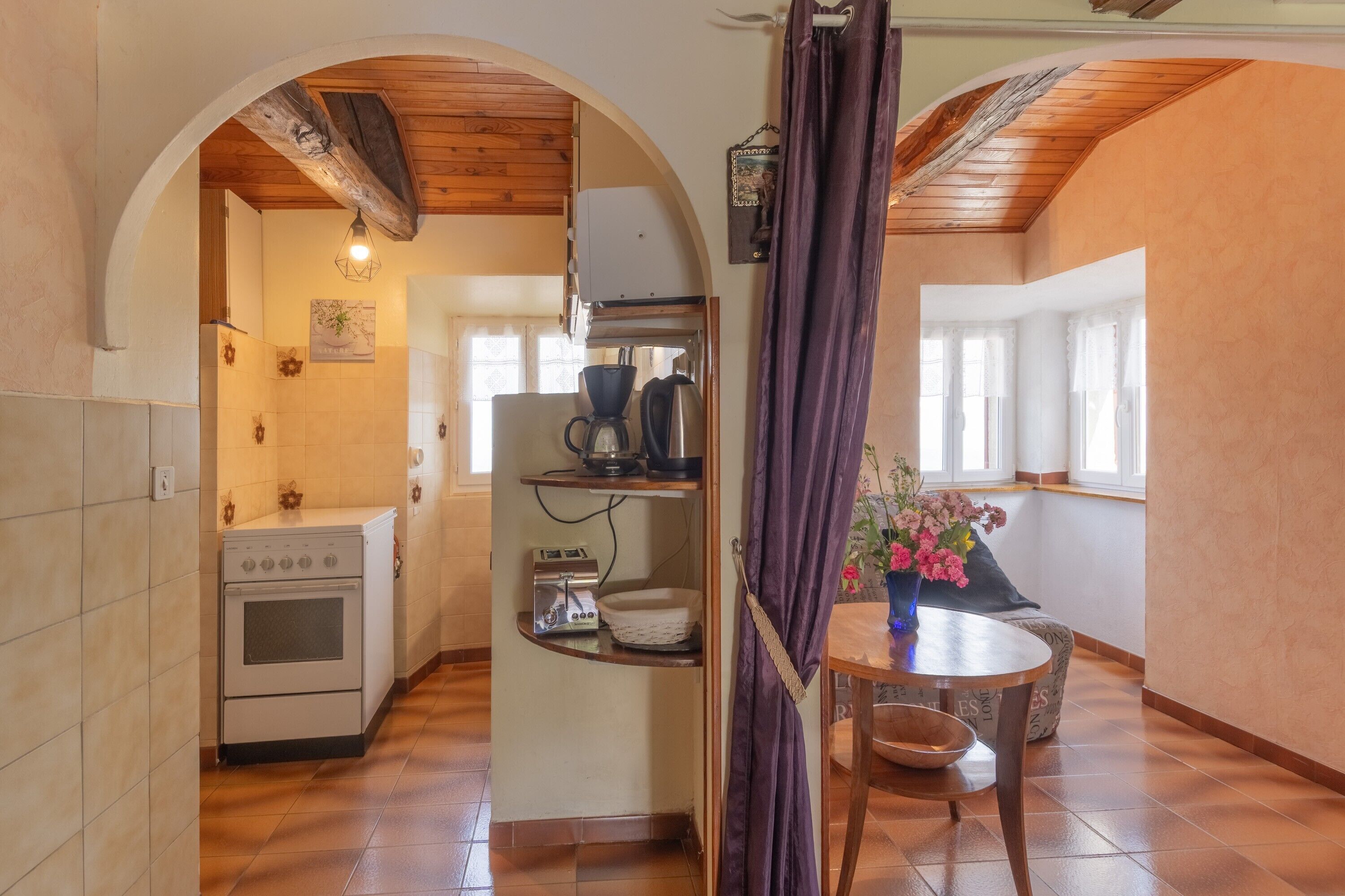 A kitchen with an oven, a coffee maker, and a shelf with a bowl.