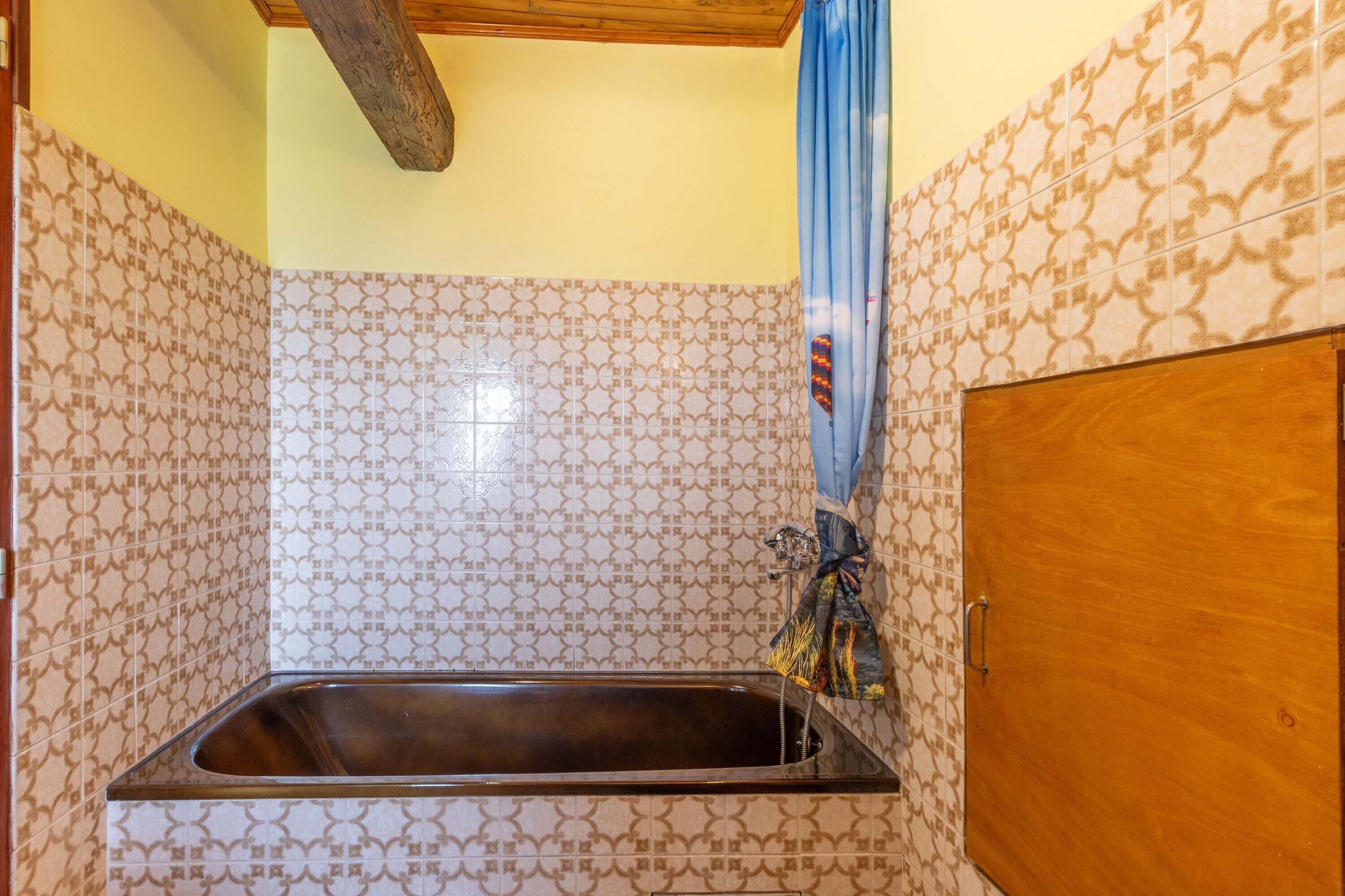Een badkamer met patroon betegelde vloer, een houten deur en een douchegordijn.