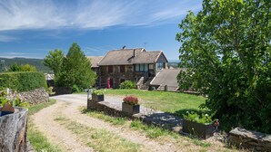 A stone house with a tiled roof, a gravel driveway, and a large tree to the right. - Holiday Home 'Le Pigeonnier' with Mountain View, Shared Pool and Air Conditioning (Gravières)