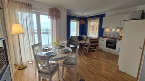A modern kitchen with white cabinets, a dining area with a round table, and a sofa. - Hausboot in Barth am Barther Bodden (Barth)