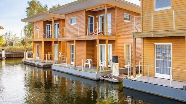 A wooden houseboat with multiple decks, outdoor seating, and a dock. - Hausboot in Barth am Barther Bodden (Barth)
