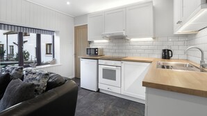 Una cocina moderna con armarios blancos, horno empotrado, microondas y un lavabo.
