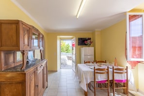 Une cuisine avec des meubles en bois, une table à manger avec des chaises, un réfrigérateur et une fenêtre donnant sur un beau paysage.