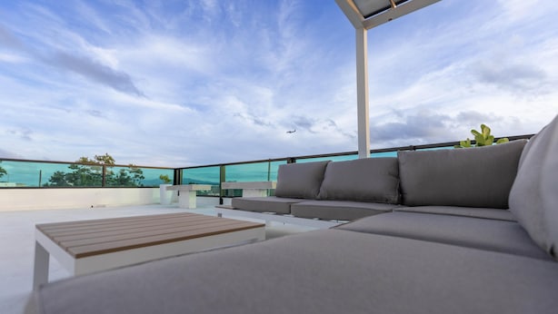 Ein moderner Außenbereich zum Sitzen mit einer Couch und einem Holztisch, mit Blick auf eine reizvolle Aussicht.