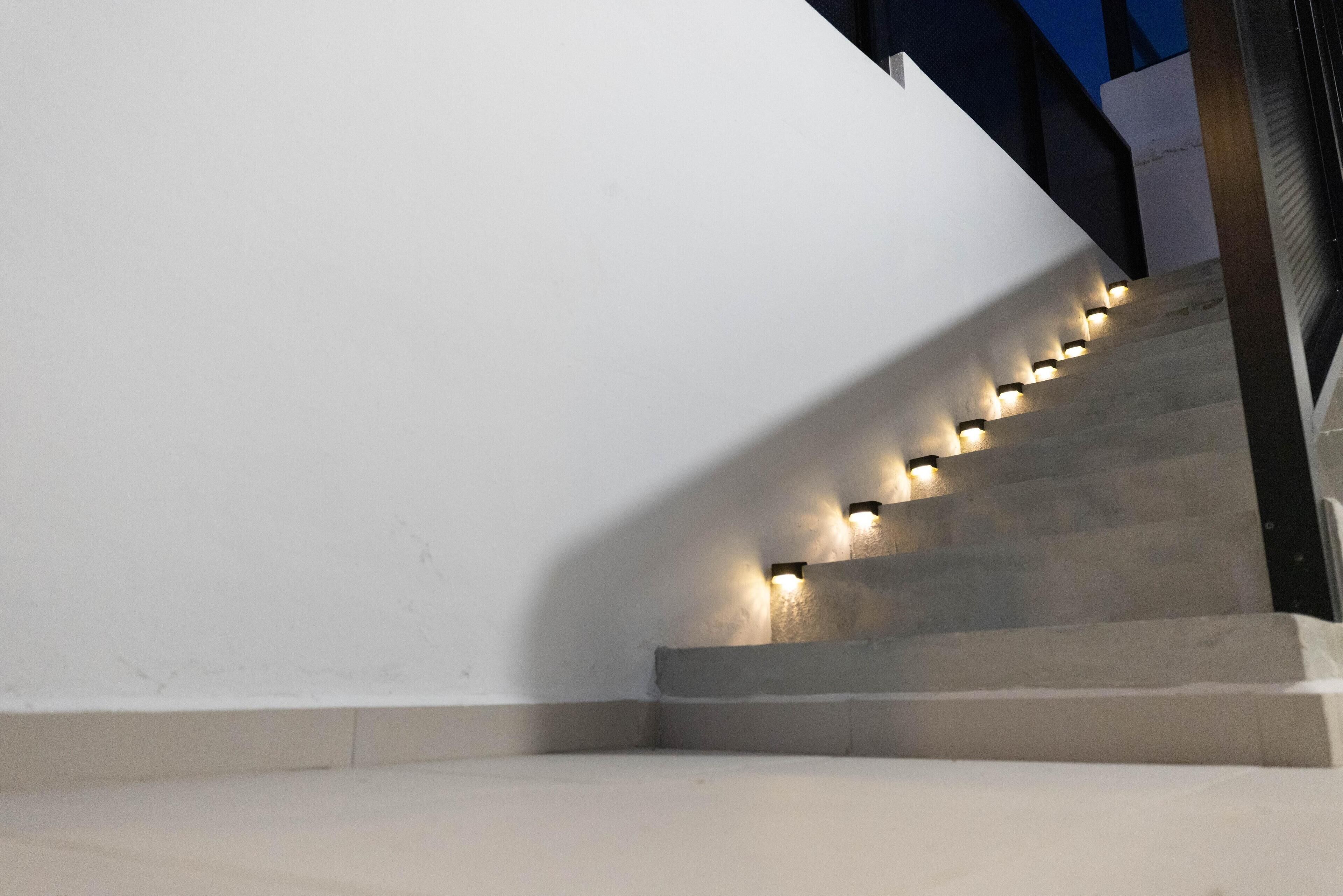 Een trap met verlichte leuningen en treden, leidend naar een plateau.
