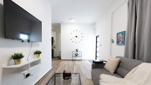 Ein modernes Wohnzimmer mit einem Flachbildfernseher, einer großen Wanduhr, einem Sofa und einem Couchtisch.