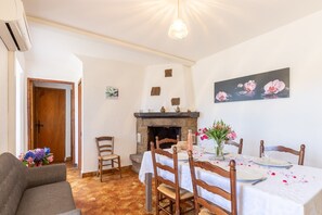 A dining area with a fireplace, wooden chairs, a table set for four, and a painting on the wall. - Holiday Home 'La Grange' with Mountain View, Shared Pool and Air Conditioning (Gravières)