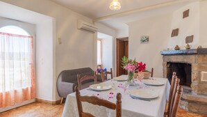Comedor con una mesa dispuesta para cuatro, chimenea y ventana con cortinas.
