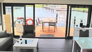 Un interno moderno con un'ampia porta scorrevole in vetro che si apre su una terrazza con vista su un canale.