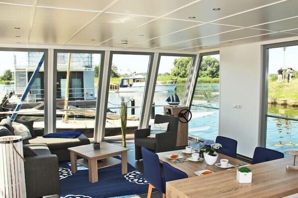 A modern interior with large windows, a dining area, and a view of the water outside.