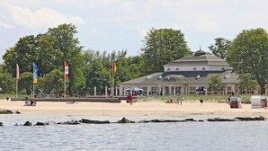 A building with a dome roof, located near a beach with flags and trees. - Hausboot in Ueckermuende (Ueckermünde)