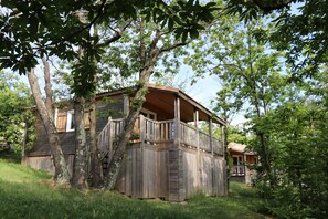 Une cabane en bois avec un porche, entourée d’arbres.