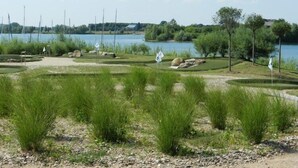 A golf course with a lake in the background, surrounded by trees and grassy areas.