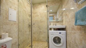 Ein Badezimmer mit Duschkabine, Waschmaschine und Toilette.