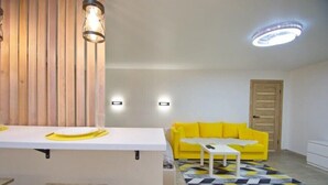 Ein modernes Wohnzimmer mit einem gelben Sofa, einem weißen Couchtisch und einem Teppich mit geometrischem Muster.