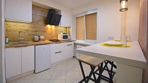 Eine moderne Küche mit weißen Schränken, einer Holz-Spritzschutzwand, einer eingebauten Mikrowelle und einer weißen Arbeitsplatte.