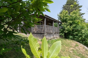 Een houten chalet met een veranda, omgeven door bomen en gras.