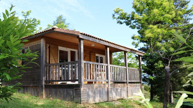 Eine Holzhütte mit Veranda, umgeben von Bäumen.