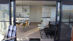 A modern kitchen with white cabinets, a dining area with a table and chairs, and a living area with a sofa and a coffee table.