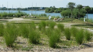 A golf course with a lake in the background, surrounded by trees and grassy areas.