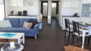 A modern living room with a blue sofa, a coffee table, and a dining area with a wooden table and chairs.