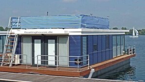 A floating house with a deck, a covered upper deck, and a website address visible.