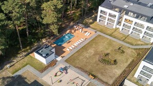 A modern building with a rooftop pool, outdoor seating, and a playground.