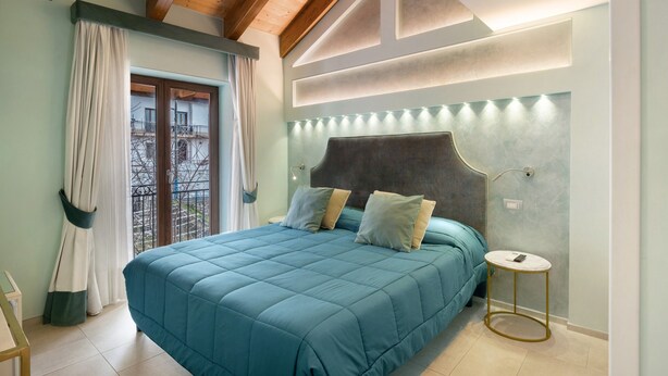 A bedroom with a large bed, a bedside table, a window with curtains, and a balcony view. - Room 'La Ciociara' with Balcony, Wi-Fi and Air Conditioning (Agerola)