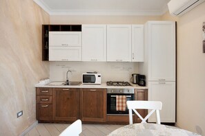 A compact kitchen with white cabinets, a microwave, a gas stove, and a refrigerator.