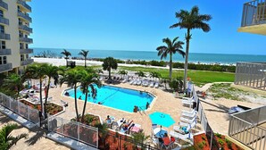 A hotel with a pool area, palm trees, and a view of the beach.