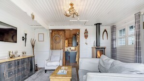 A cozy living room with a fireplace, a wooden coffee table, a white armchair, and a grey sofa. - 1 bedroom accommodation in Hexham (Hexham)
