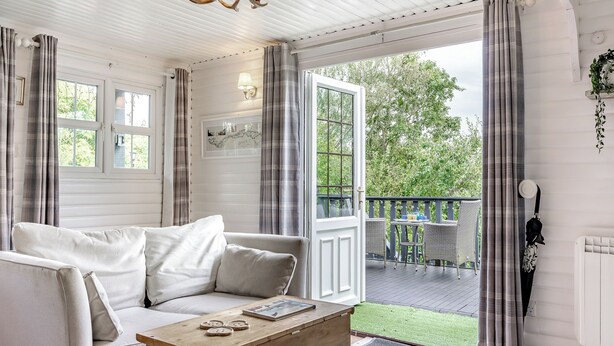A cozy room with a white sofa, a wooden coffee table, and a view of a balcony with a railing. - 1 bedroom accommodation in Hexham (Hexham)