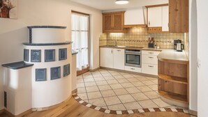 A kitchen with wooden cabinets, a tiled backsplash, and a built-in oven. - Apartment 'Désirée - Fanes' with Mountain View, Balcony and Wi-Fi (St. Vigil)