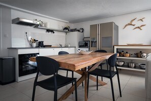 Una cocina moderna con una mesa de madera, sillas negras, armarios blancos y un microondas.