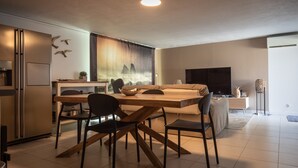 A modern hotel room with a bed, a desk, a chair, a TV, and a refrigerator.