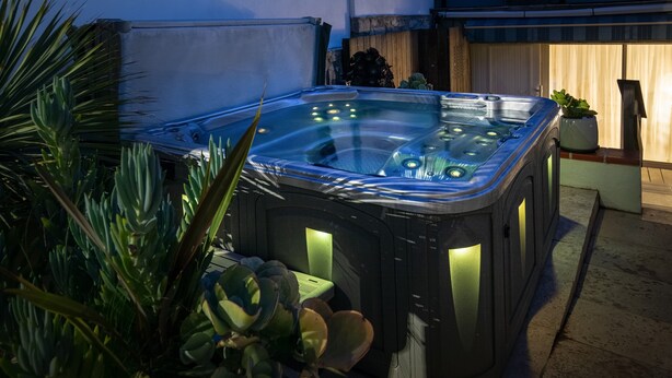 A hot tub in an outdoor setting with surrounding plants.