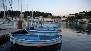 A marina with several small boats docked, calm water, and buildings in the background.