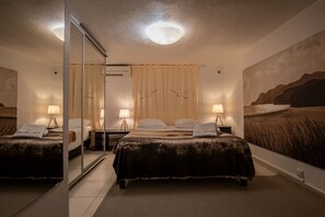 Une chambre d’hôtel avec deux lits, un grand miroir, un luminaire au plafond et un tableau accroché au mur.