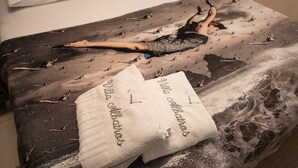 A bed with a patterned cover, a white pillow with text, and a person lying on it.