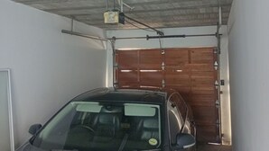 A car parked inside a garage with a concrete ceiling and a wooden door. - 3-bedroom apartment in charming Walvis Bay with AC, WiFi (Walvis Bay)