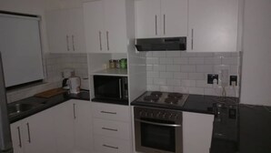 A modern kitchen with white cabinets, a black countertop, a microwave, a stove, and a coffee maker. - 3-bedroom apartment in charming Walvis Bay with AC, WiFi (Walvis Bay)
