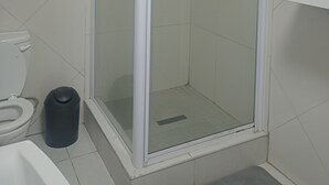 A bathroom with a glass-enclosed shower, a toilet, and a trash bin. - 3-bedroom apartment in charming Walvis Bay with AC, WiFi (Walvis Bay)