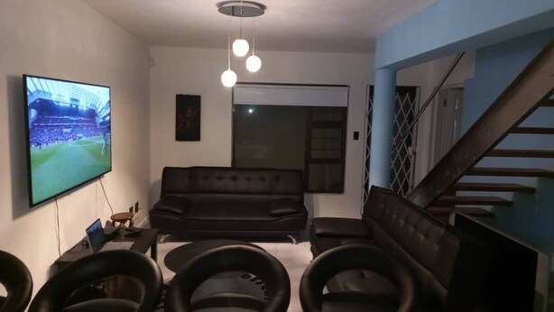A living room with a TV, a sofa, a dining table, and a staircase. - 3-bedroom apartment in charming Walvis Bay with AC, WiFi (Walvis Bay)