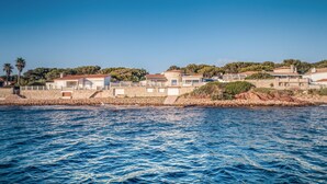 A coastal property with a stone wall, multiple buildings, and a view of the sea.