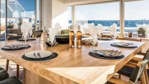 A dining table set for six with a view of the sea.