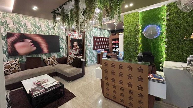 A modern reception area with a green wall, a reception desk, a sofa, and a television. - HOTEL INDRALOK INN (Hazaribagh)